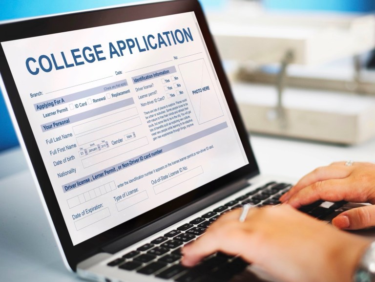 A student filling out a college application on a laptop